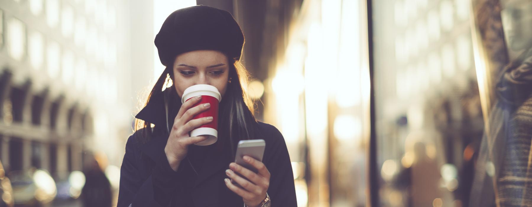 woman looking at her phone on city sidewalk