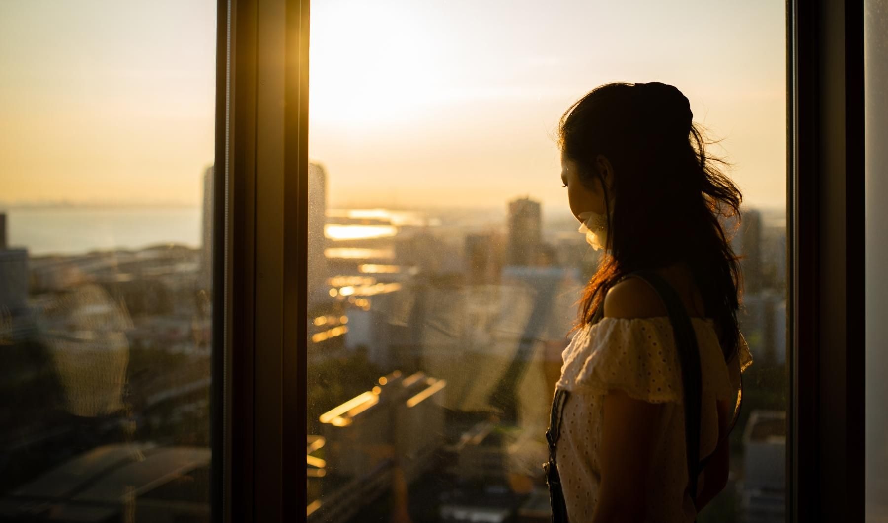 woman looking out a window at city view