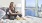 a woman sitting on a bed looking out her window