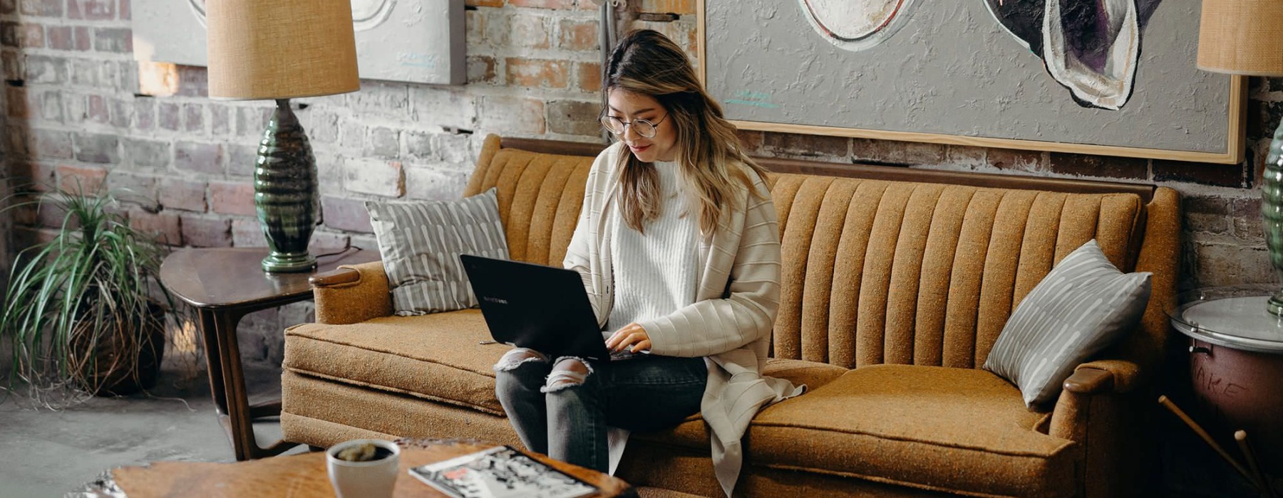 woman sitting on couch working on laptop
